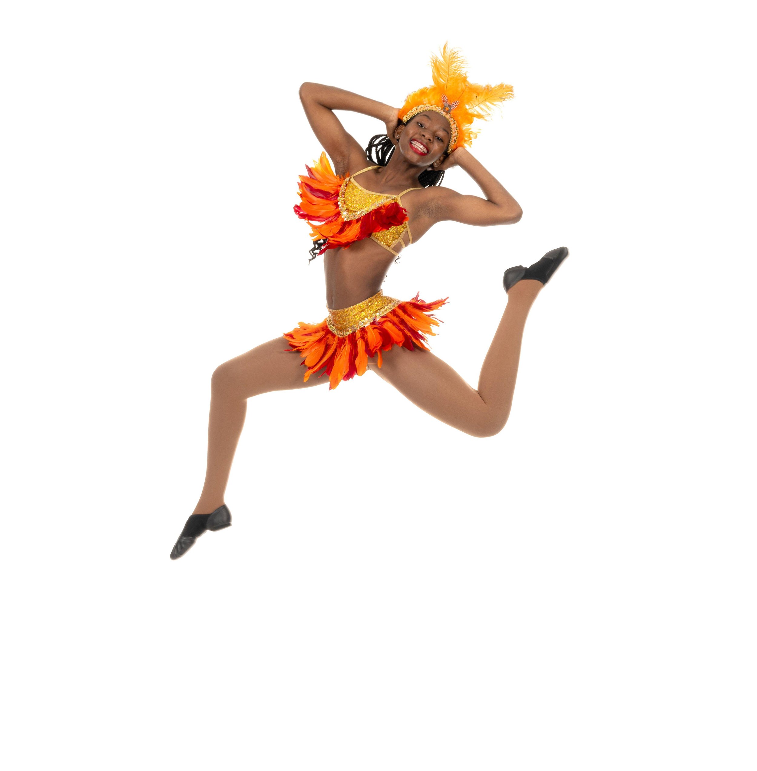 Niq is dressed in a colorful flamenco dance costume with orange, yellow, and red feathers, wearing a matching headpiece, smiling and striking a dynamic dance pose.