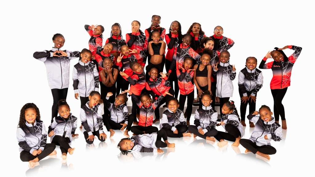 Group of young girls in black, red, and white athletic wear posing together against a white background.