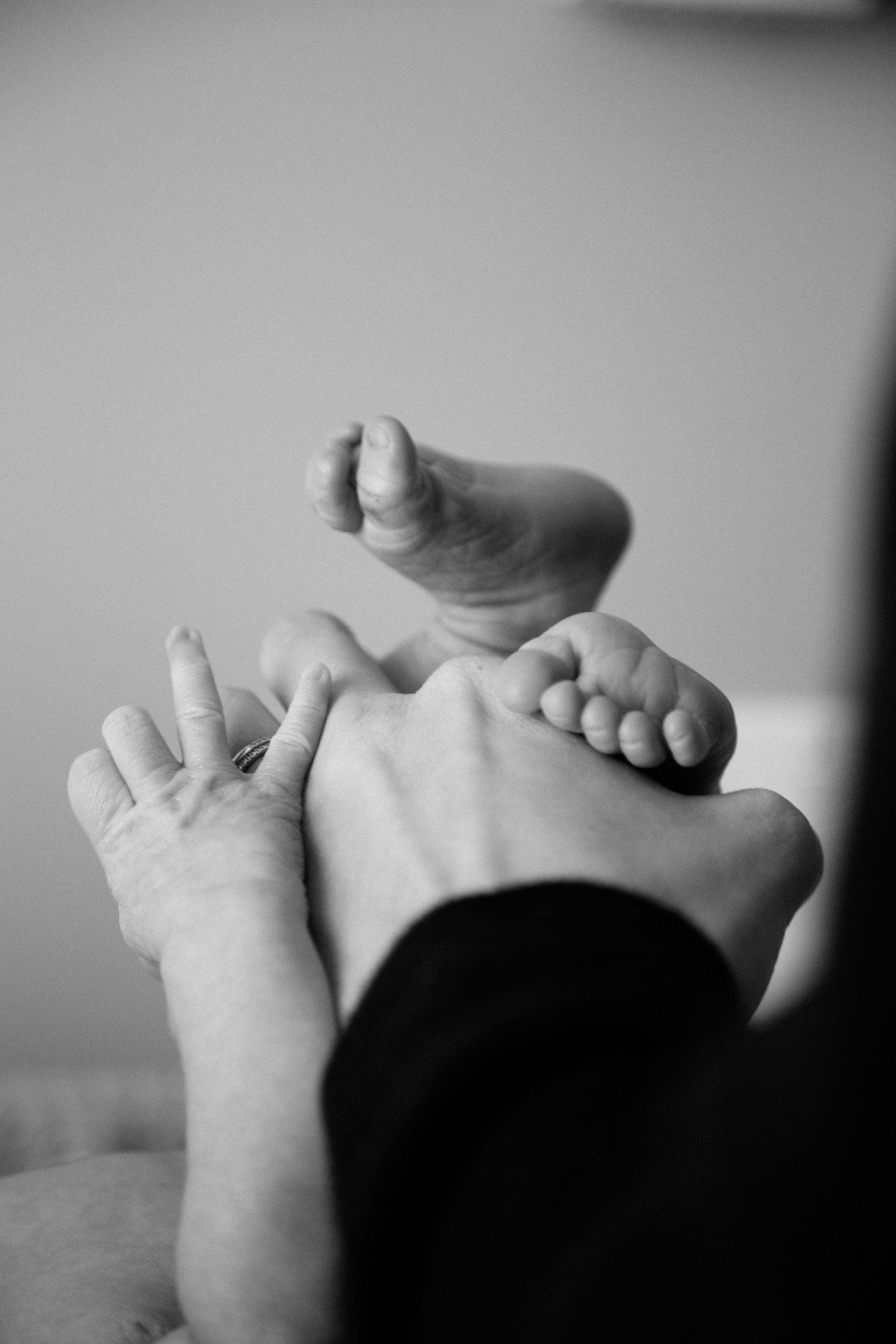 Close-up of multiple hands layered on top of each other, including a baby's hand, an adult hand, and one hand with a ring.