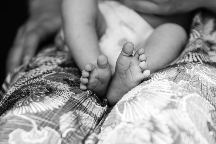 A close-up of baby feet resting on patterned fabric.