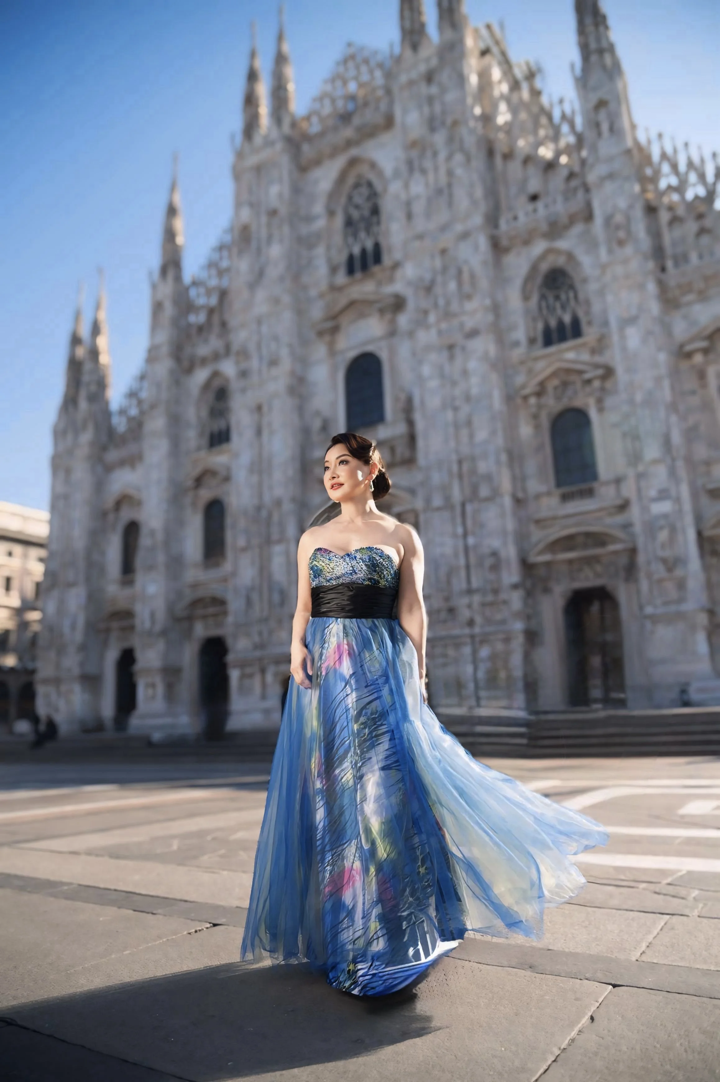 Winnie Wen in a colorful, flowing evening gown stands in front of the Duomo di Milano, with the cathedral's ornate Gothic architecture and spires visible behind her.