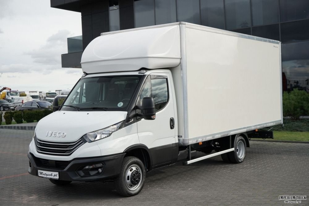 Een wit Iveco verhuiswagen geparkeerd op een weg naast een modern gebouw.