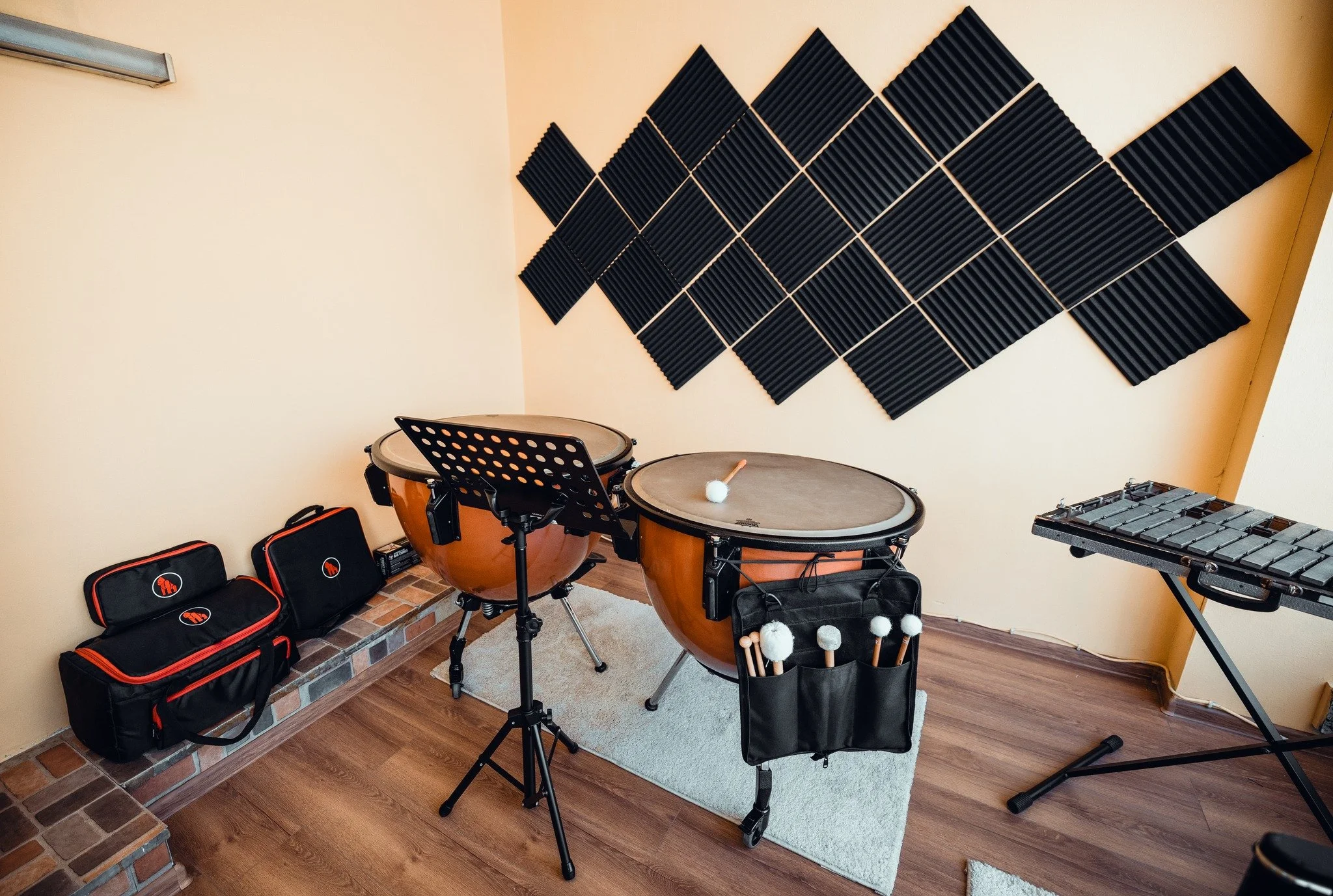 A room with musical instruments including timpani, a xylophone, and drums, with soundproof black foam wall panels.