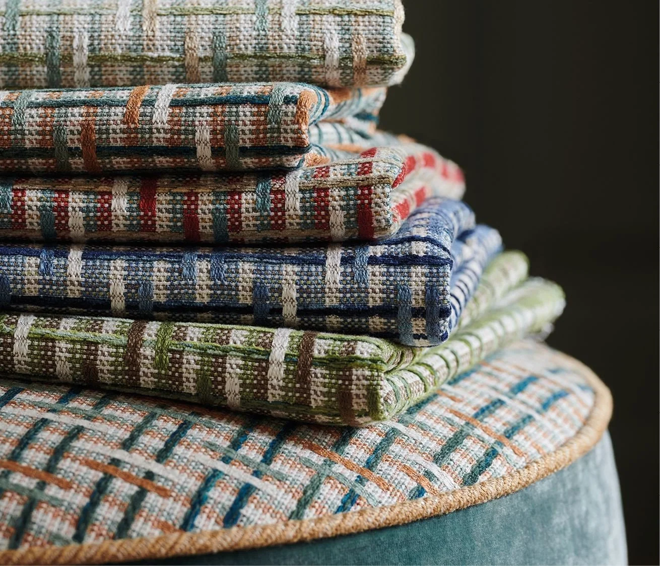 Stack of folded checked and patterned fabric pieces on a round surface.