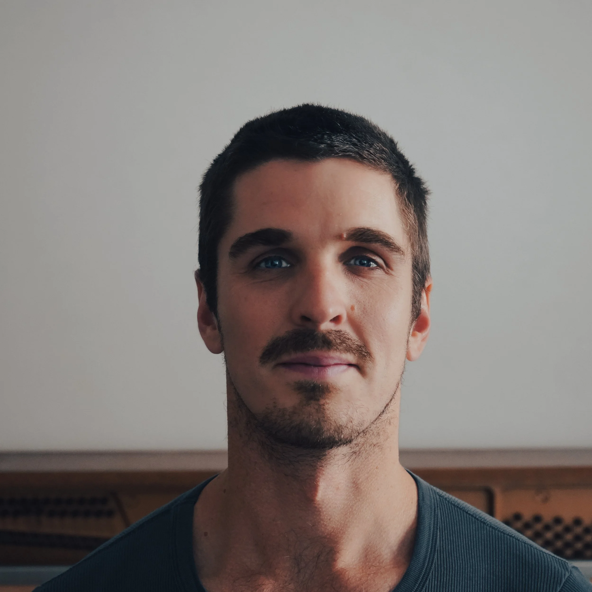 Close-up of a person's face showing the eyes, eyebrows, forehead, and part of the nose, with a plain light gray background.