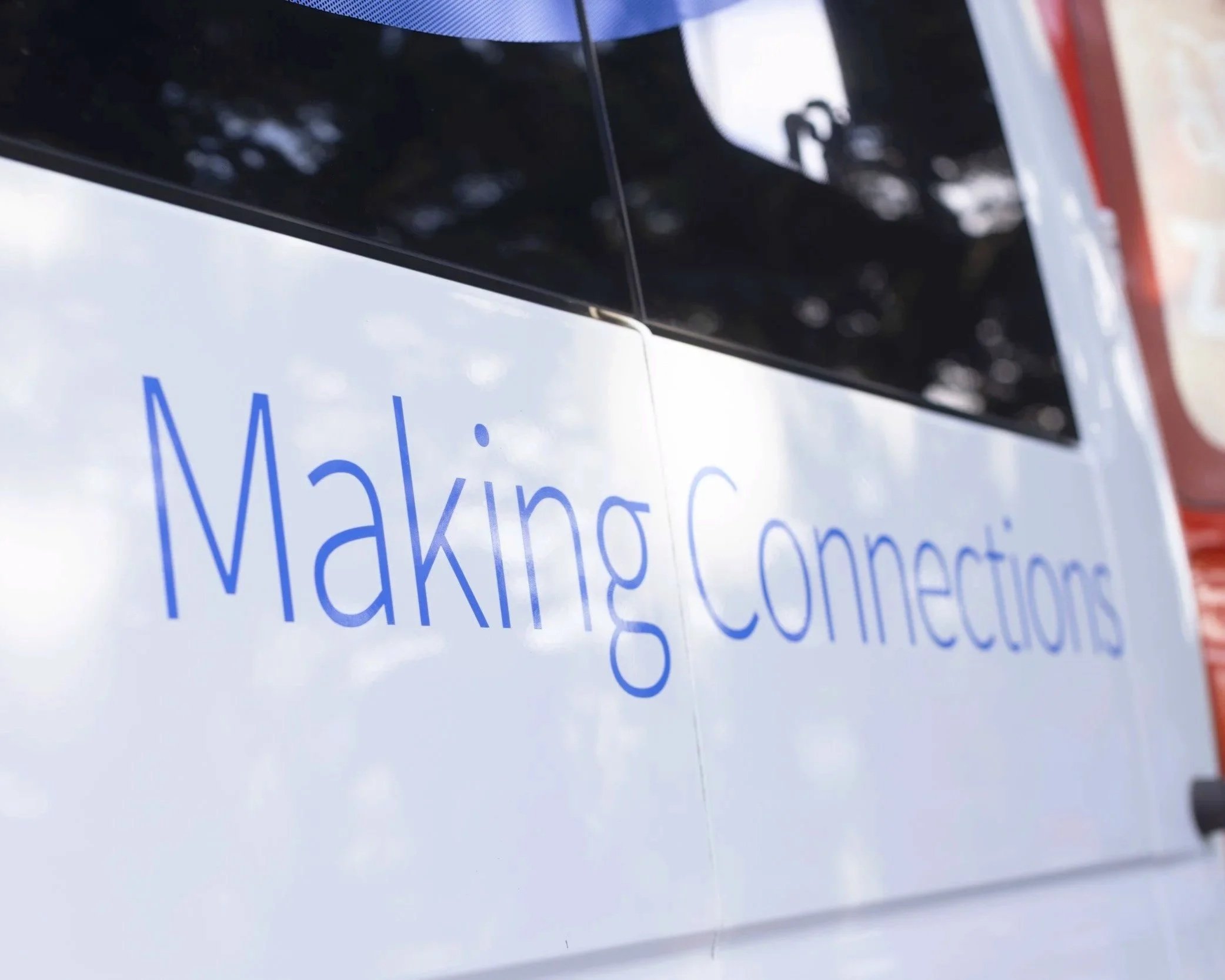 Close-up of a sign with partially visible text, showing the letters 'M', 'a', 'k', 'i', 'n', 'g', 'a', 'n', 'd', 'o', 't', 't', 'i', 'n', 'g', and 'c', in blue font on a white background.