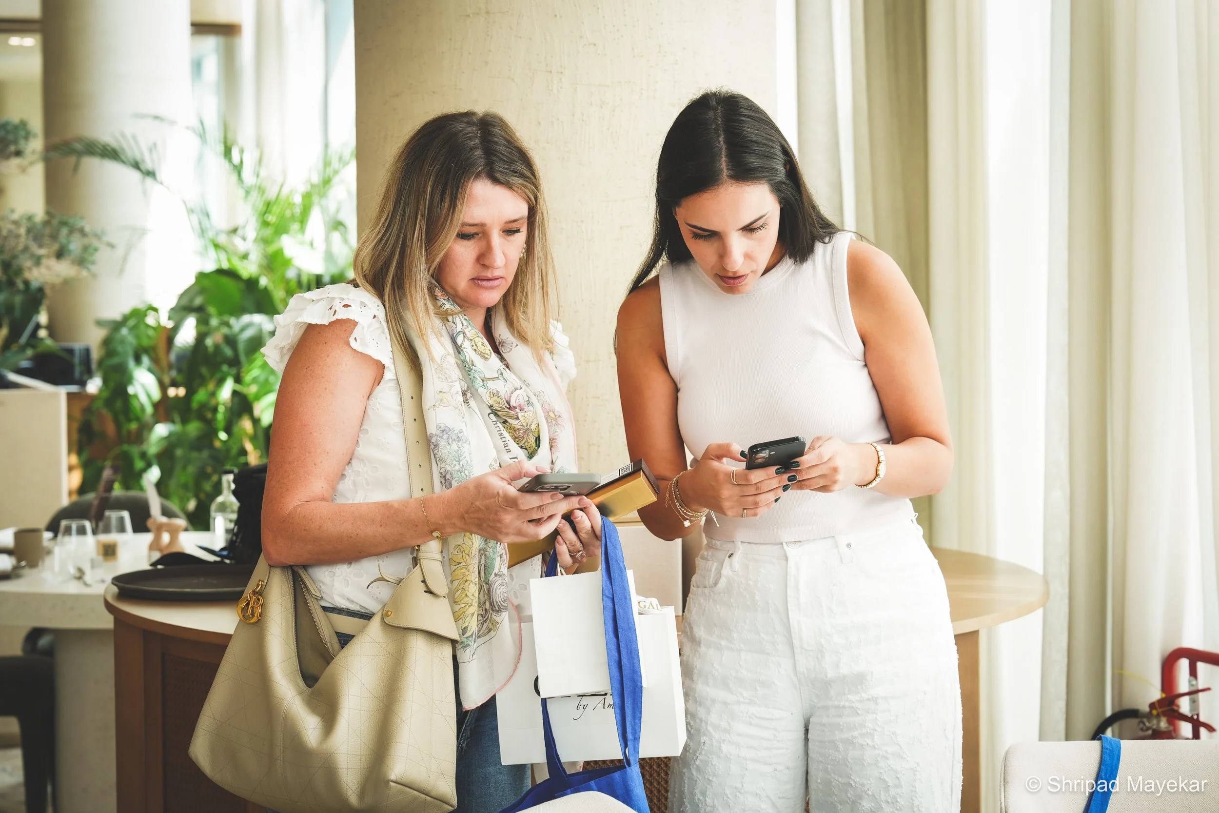 Two women exchanging contact details at a REINV8NT networking event in Dubai. She builds is a networking event for founders, entrepreneurs, and professionals in Dubai scheduled for November 14th from 10 am to 12 pm at a location with 80 seats.