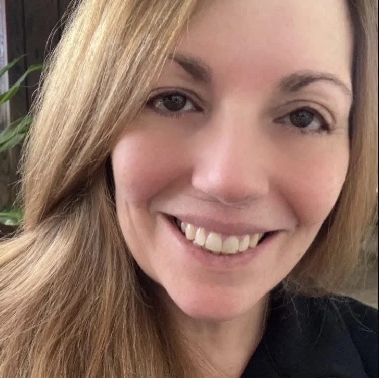 Close-up of a smiling woman with long, light brown hair and fair skin.