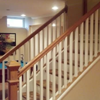 Interior view of a staircase with white spindles and a wooden handrail in a home.
