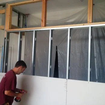 A man working on installing drywall in a building under construction.