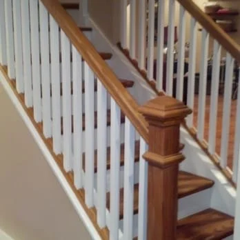 Wooden staircase with white spindles and a brown handrail.