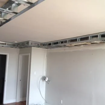 Interior room under renovation with drywall and exposed ceiling framework, no furniture or decor.