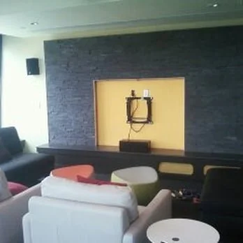 Living room with a black accent wall, a built-in shelf, and seating including a white couch and colorful chairs.