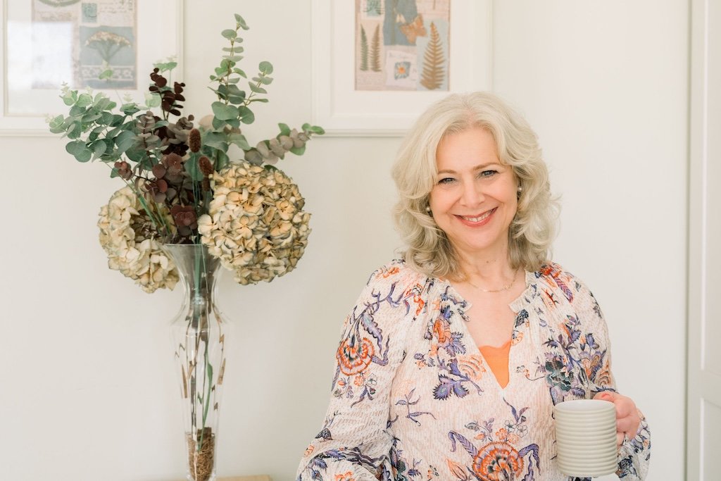 Woman smiling and holding a cup of tea in a relaxed setting