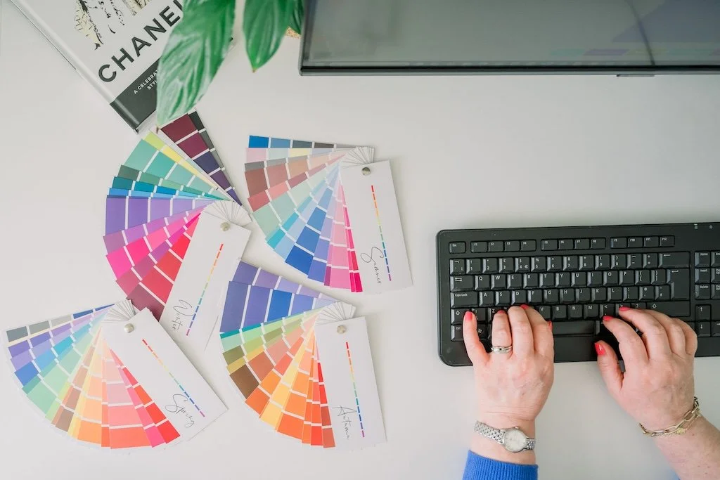 Flat lay of colour swatches, fashion book, laptop and workspace setup