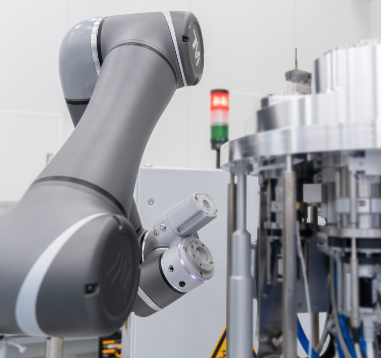 A robotic arm working in a high-tech industrial setting, surrounded by machinery and components.