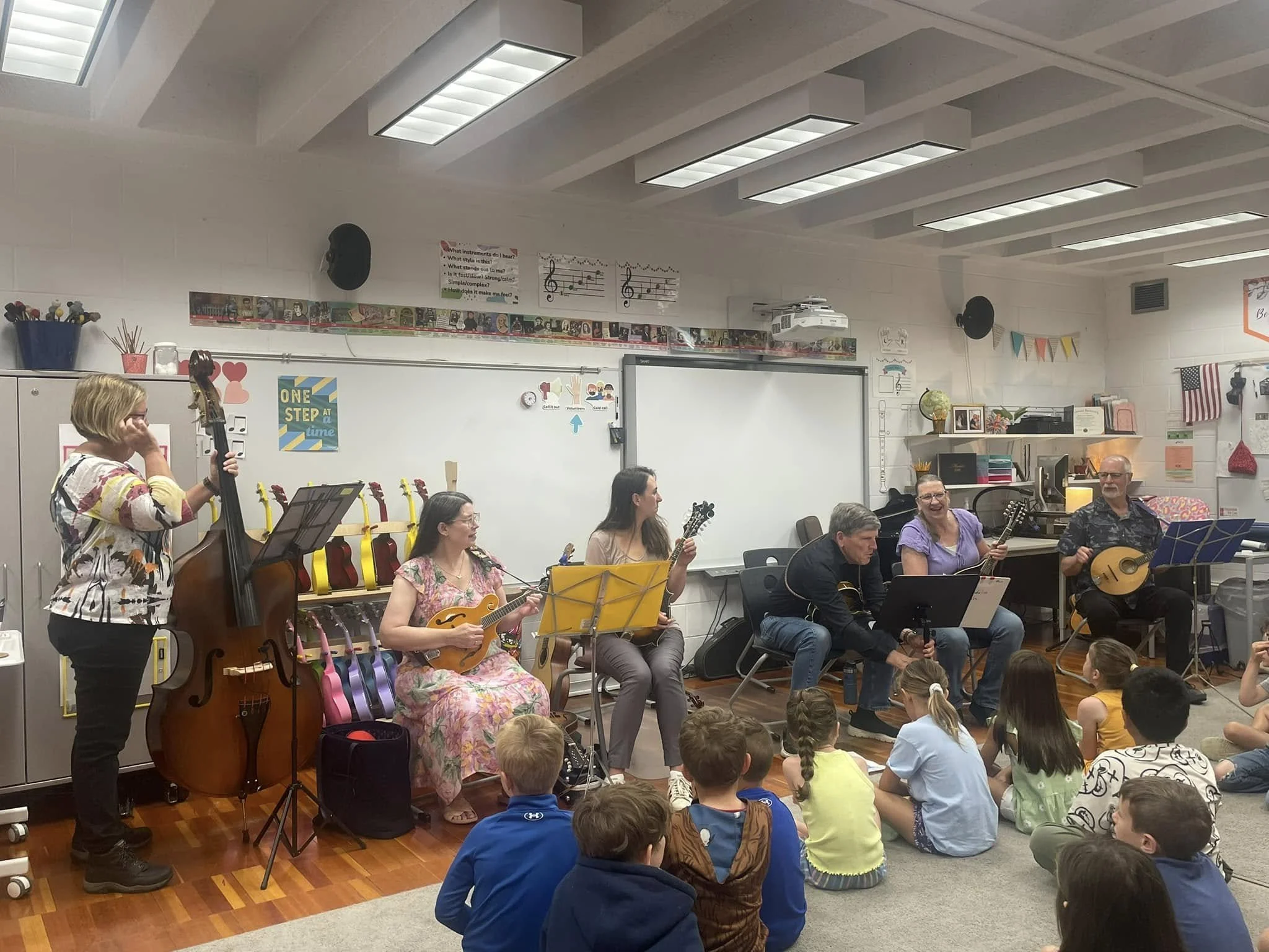Five musicians sit at the front of the classroom with mandolins and an upright bass