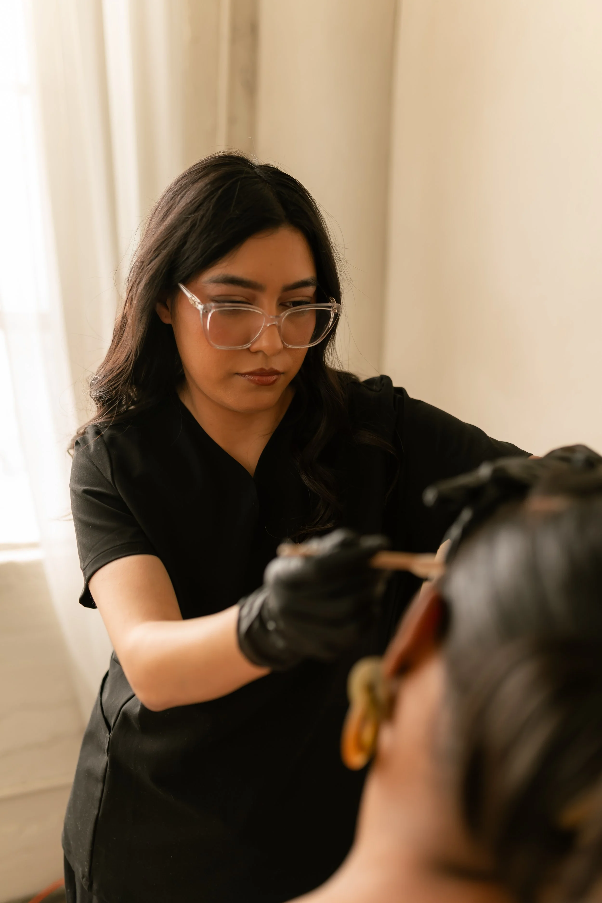 Esthetician performing face waxing on a client, carefully applying wax for smooth skin and clean facial hair removal in a professional studio.