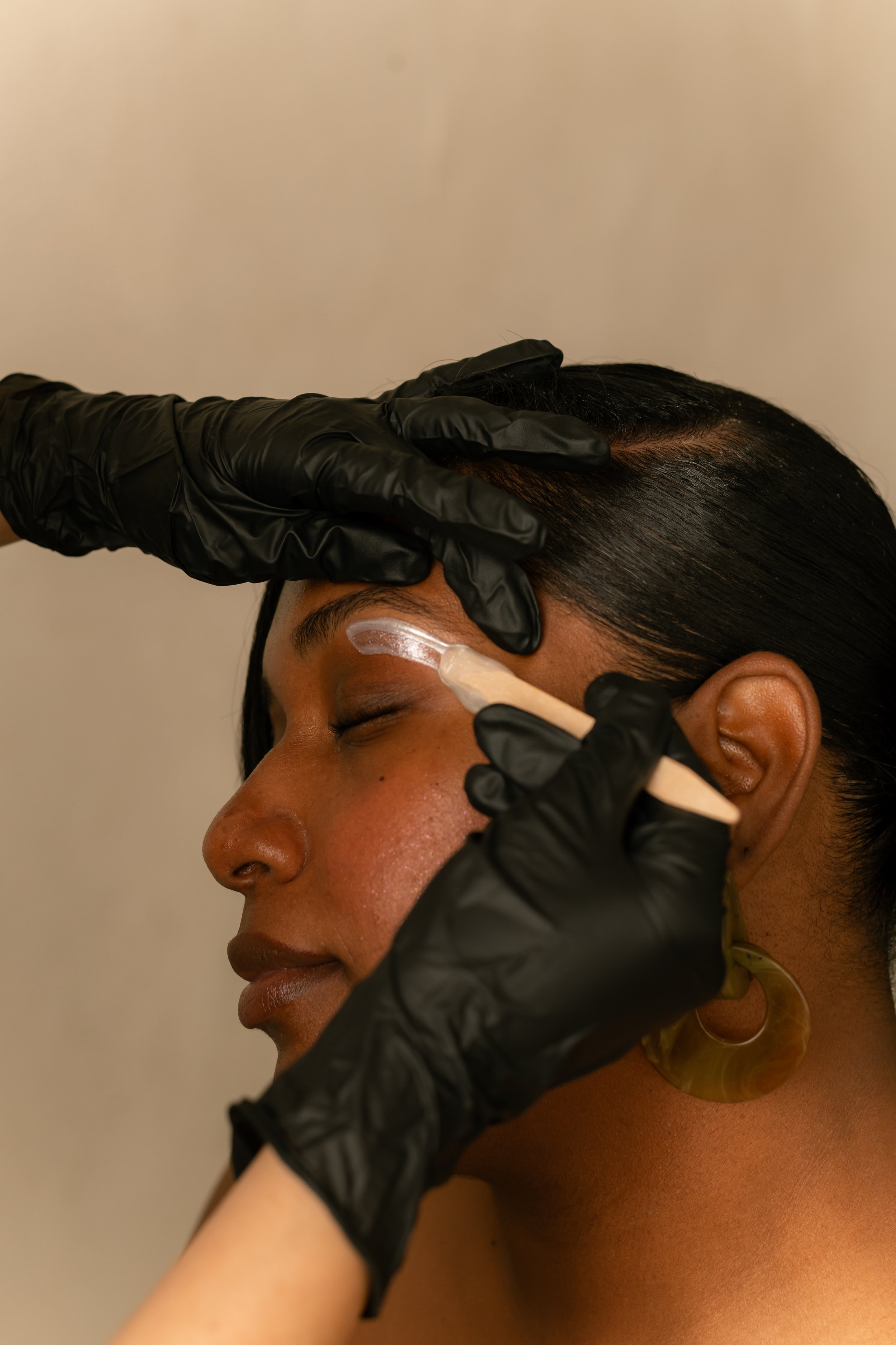 Eyebrow waxing in progress with careful wax application, shaping the brow area for a clean, polished, and natural-looking result.