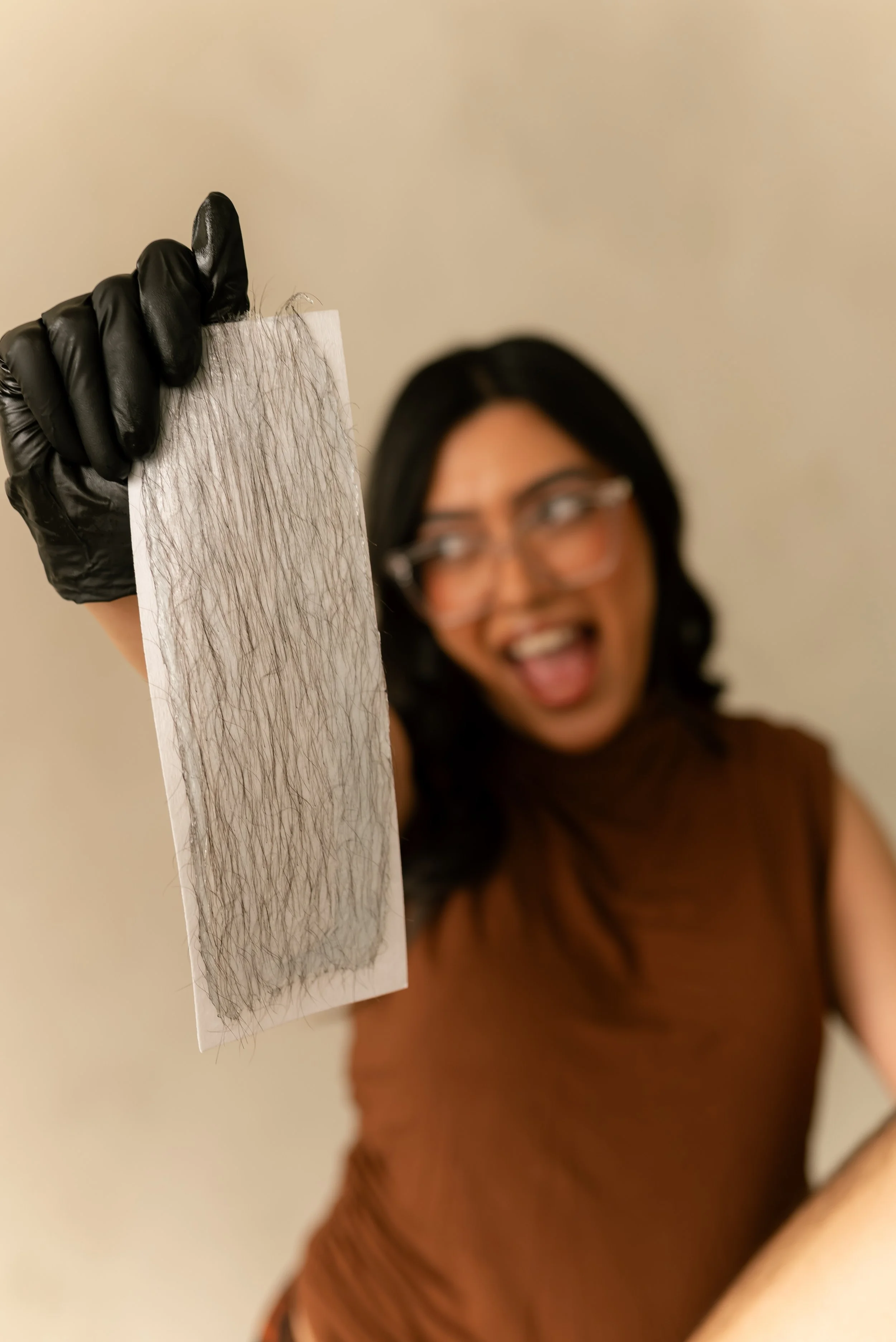 Esthetician holding used wax strip after hair removal
