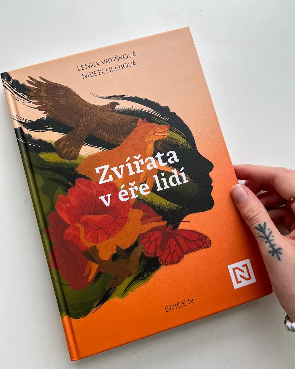 photo of book cover of zvířata v éře lidí, featuring a silhouette of a face with animals on top of it