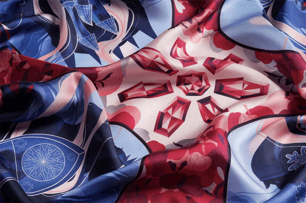 Close-up photo of a Snow White–themed scarf pattern featuring an ornate mirror surrounded by apples, gemstones, and decorative fairytale motifs.