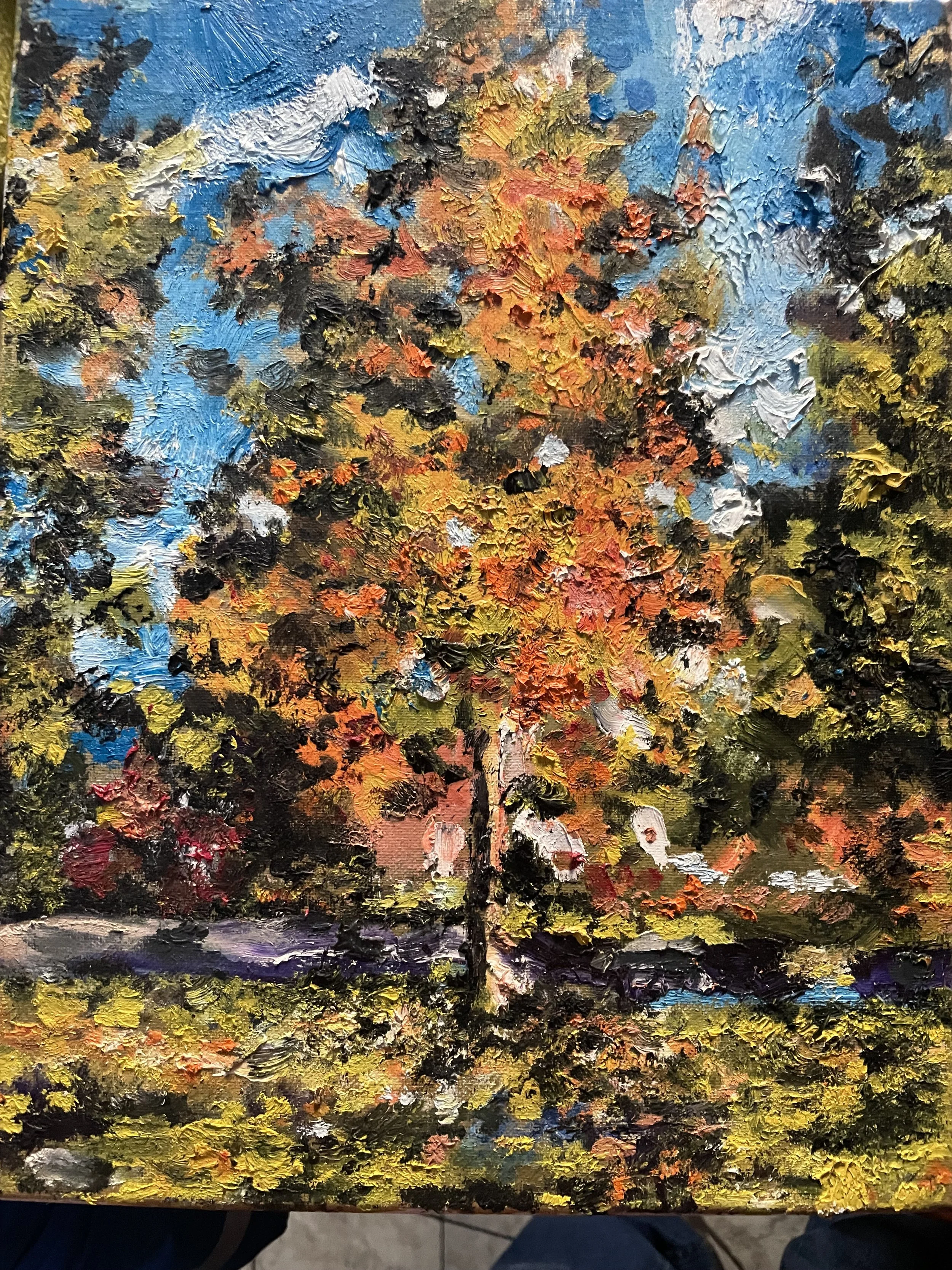 A colorful, abstract landscape painting of a tree in autumn, with bright orange, yellow, green, and black leaves, on a vibrant background with patches of blue, white, and purple, painted with thick, textured brushstrokes.