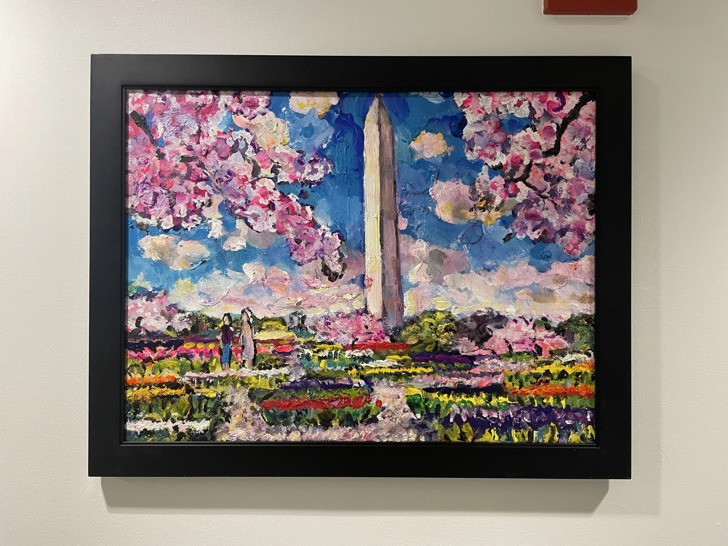 Abstract impressionist painting of cherry blossom trees in pink, purple, and white, with a blue sky background, set in a black frame.