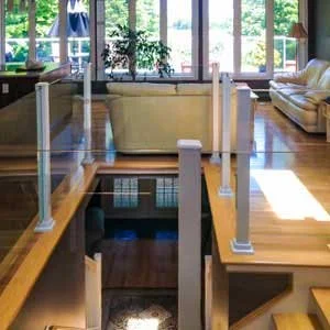 Living room with large windows, beige couches, a potted plant, and stairs leading down to an indoor pool area.