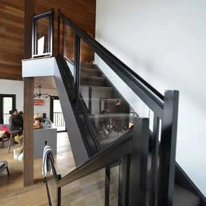 Modern staircase with glass sides and black handrails in a home interior.