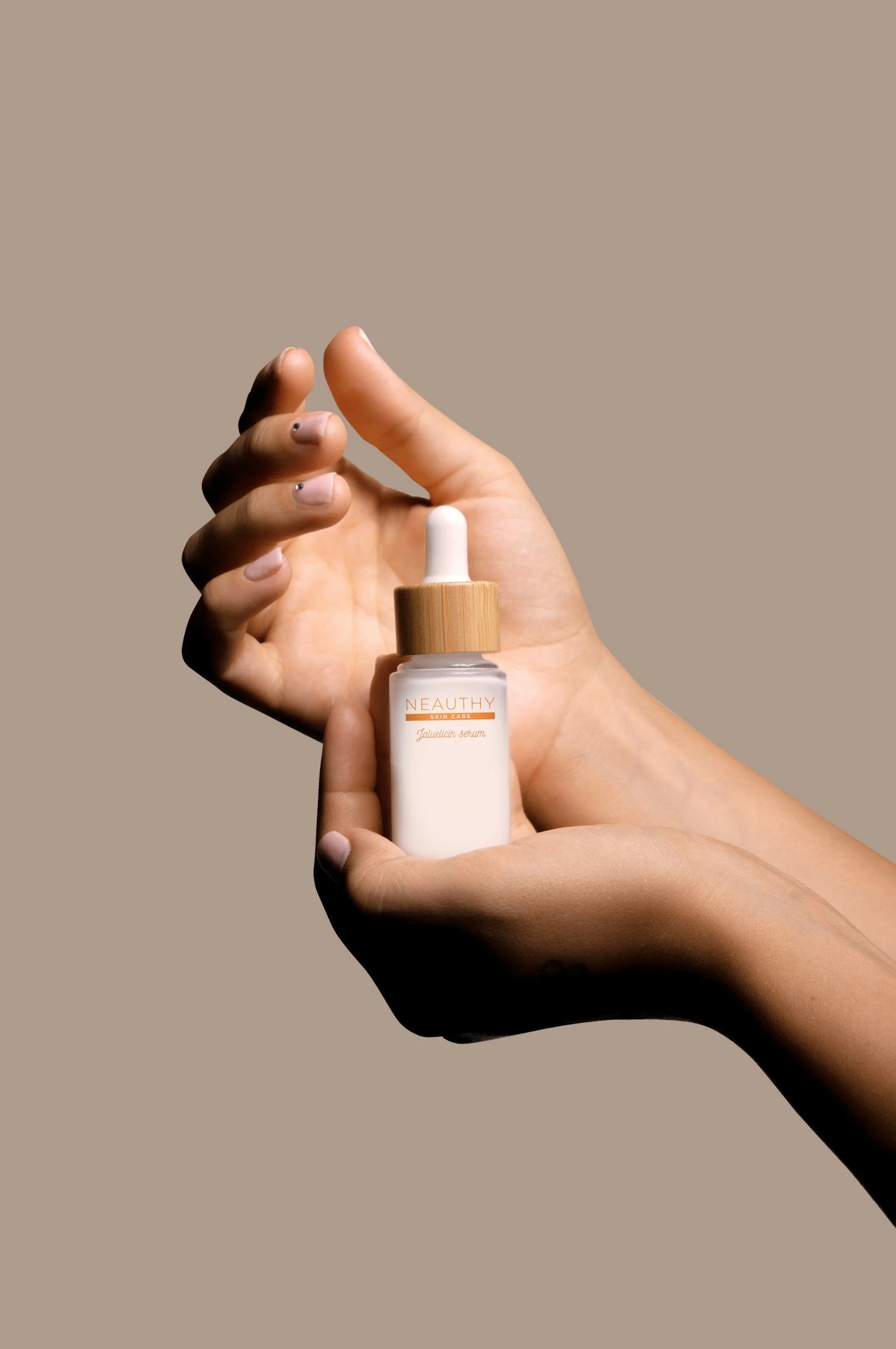Close-up of a hand holding a white bottle with a dropper cap, labeled 'NEAUTHY Skin Care' and 'Fauveicin serum', against a beige background.