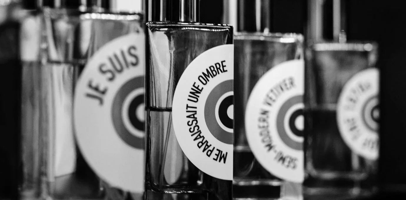 Close-up of glass jars with circular stickers that have French text, on a shelf.