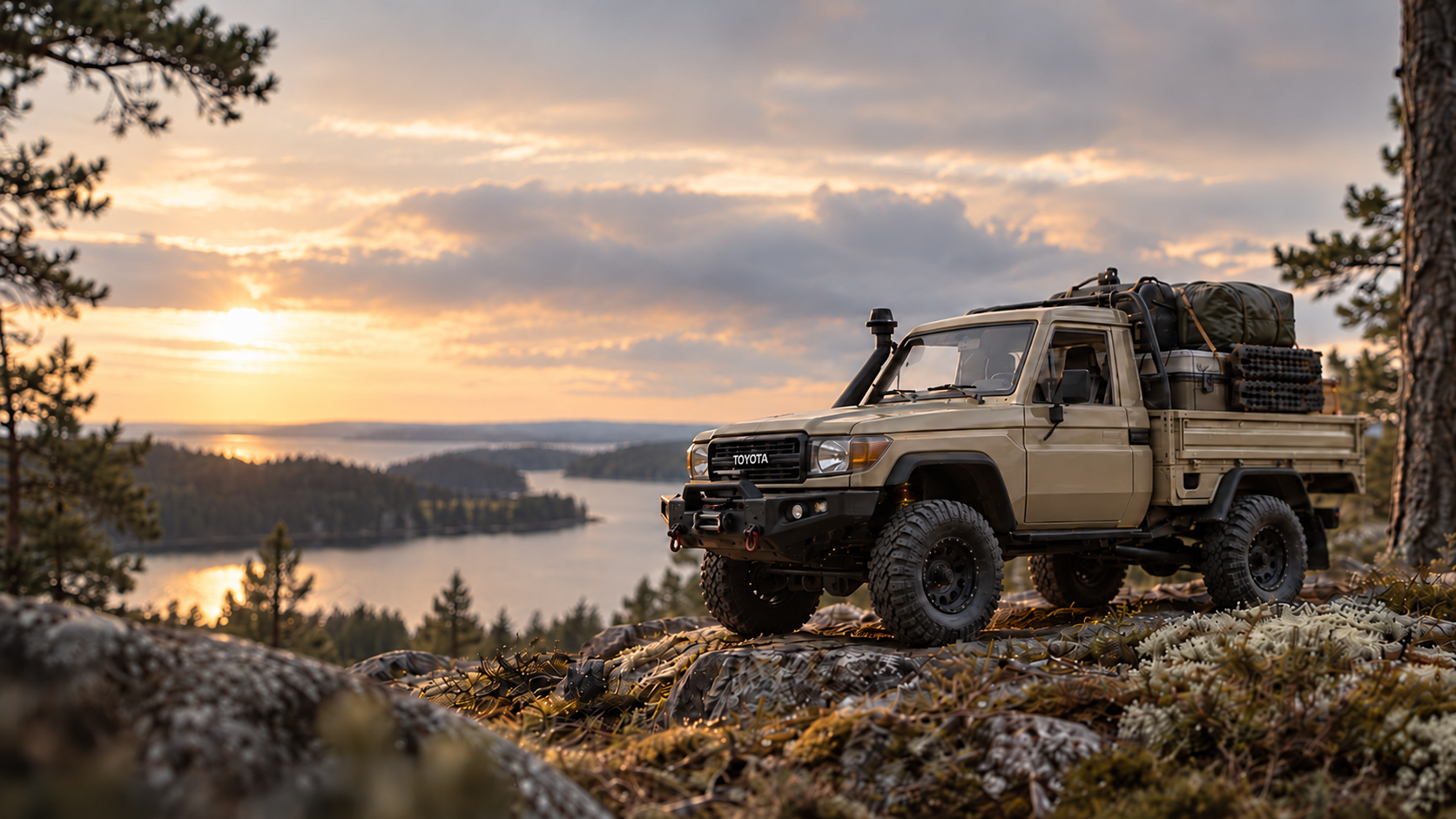 A beige super-scale overland pickup on a rocky lookout above a Finnish lake at sunset.