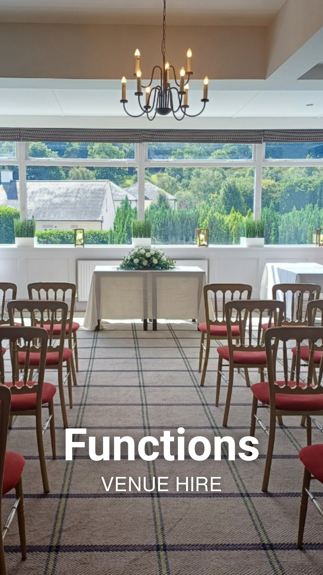 Elegant indoor event space with a chandelier, a table with a floral centerpiece, and arranged chairs, large windows overlooking a backyard with trees, with text overlay saying 'Functions Venue Hire'.