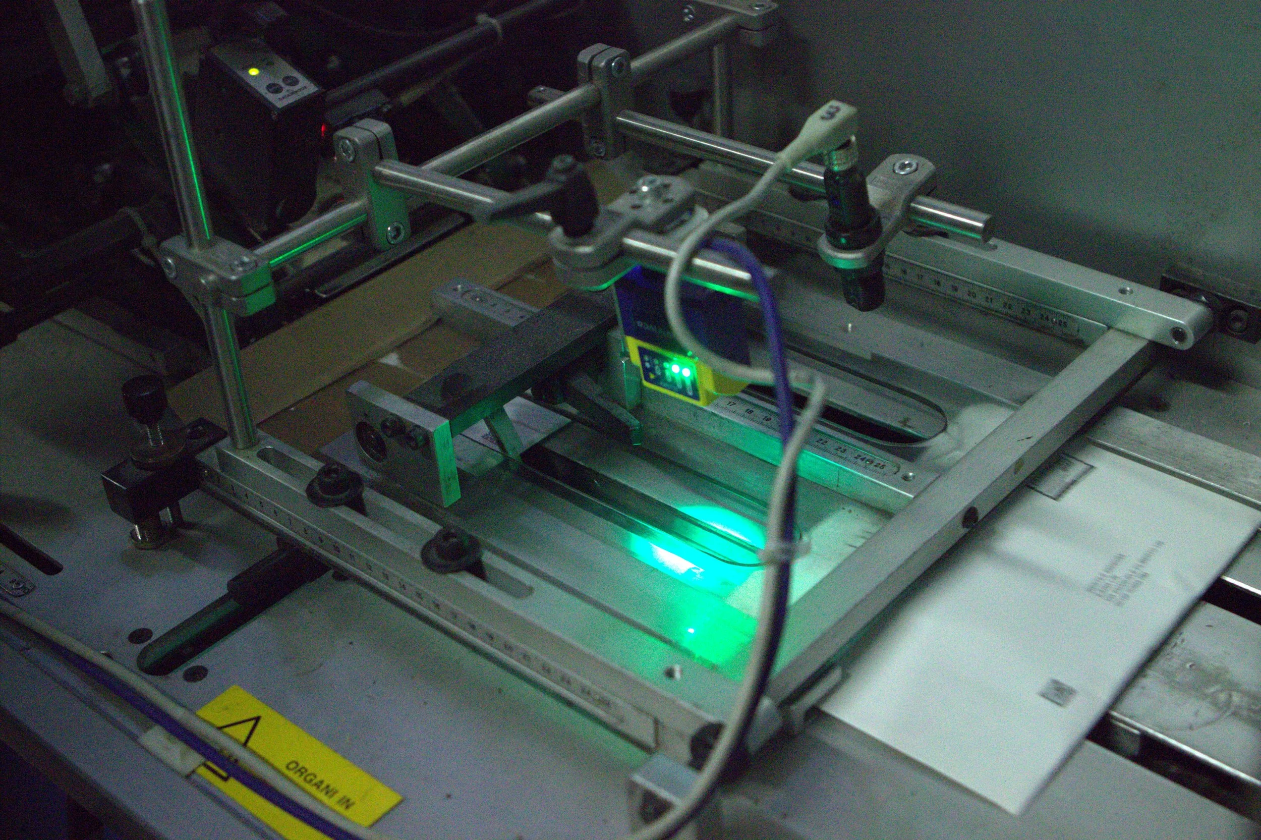 Macchina di laboratorio con componenti metallici, luci verdi e un display digitale, usata probabilmente per test o assemblaggi tecnici.