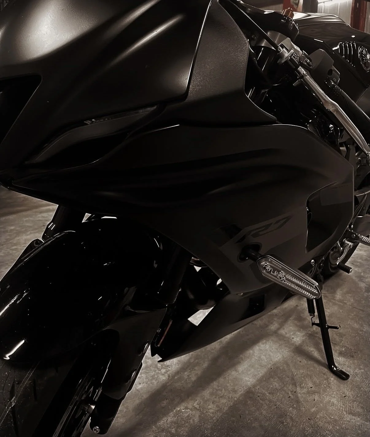 Close-up of a sleek, black motorcycle in a dimly lit indoor parking area.