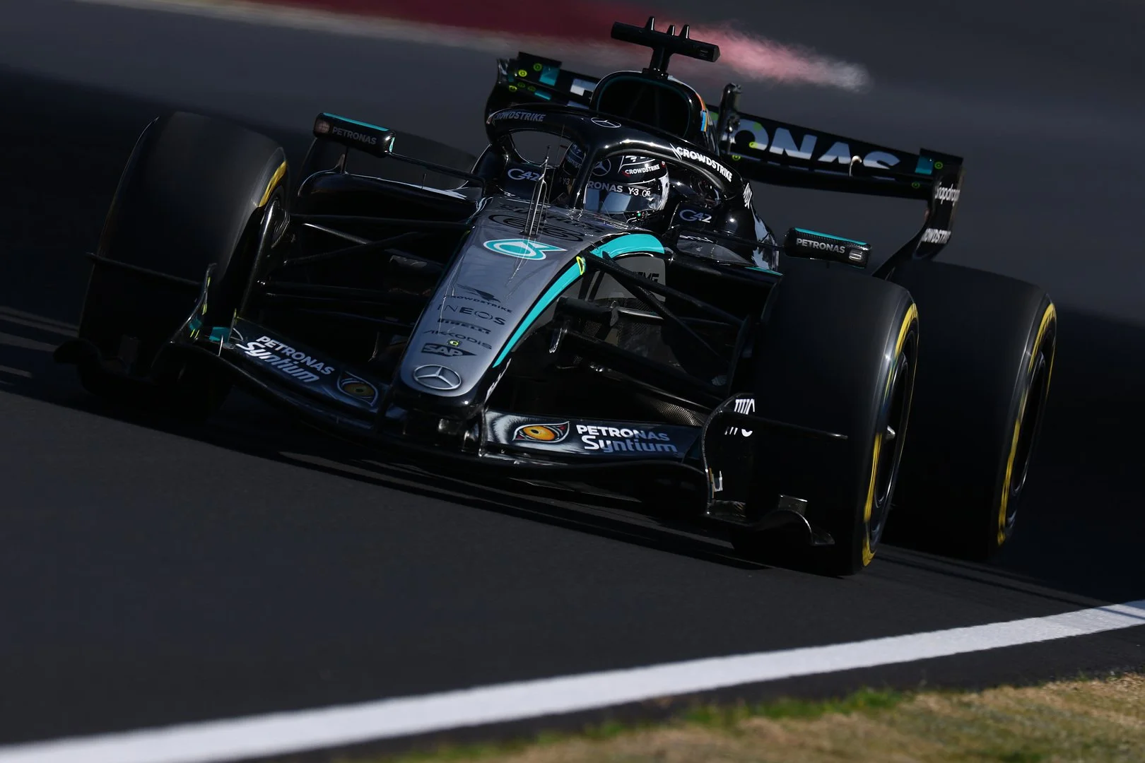 A Mercedes-AMG PETRONAS F1 car photographed head-on as it navigates a corner at the Japanese Grand Prix, with the teal and silver livery clearly visible against the grey asphalt.