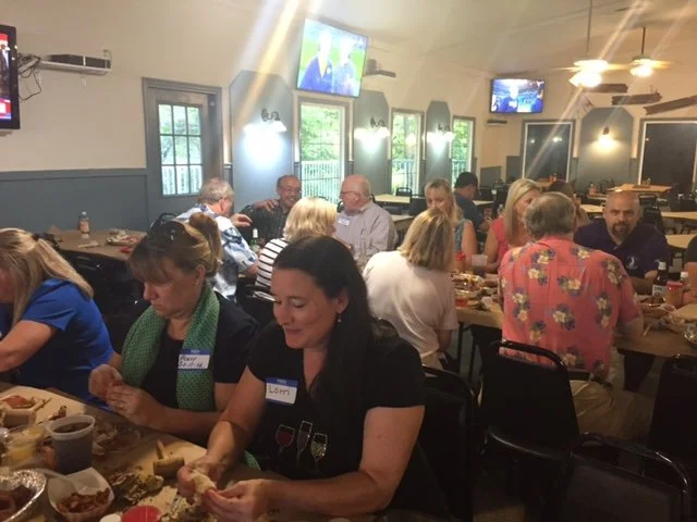 People gathered around tables eating and socializing in a restaurant with TV screens on the walls.