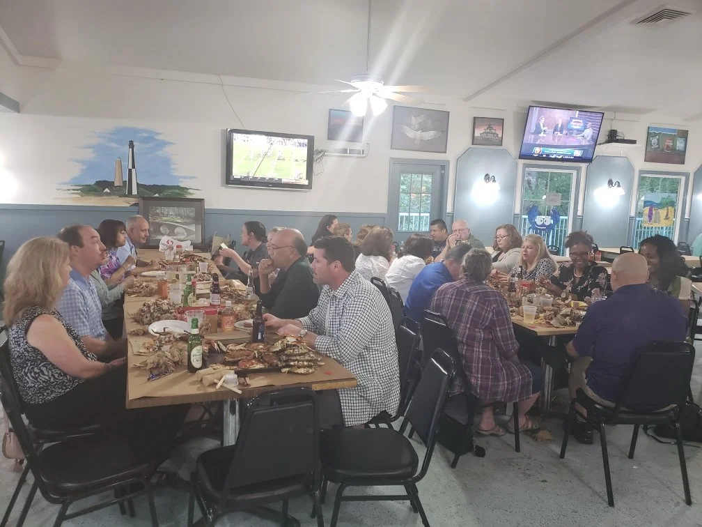 People sitting at long tables eating seafood in a decorated restaurant.