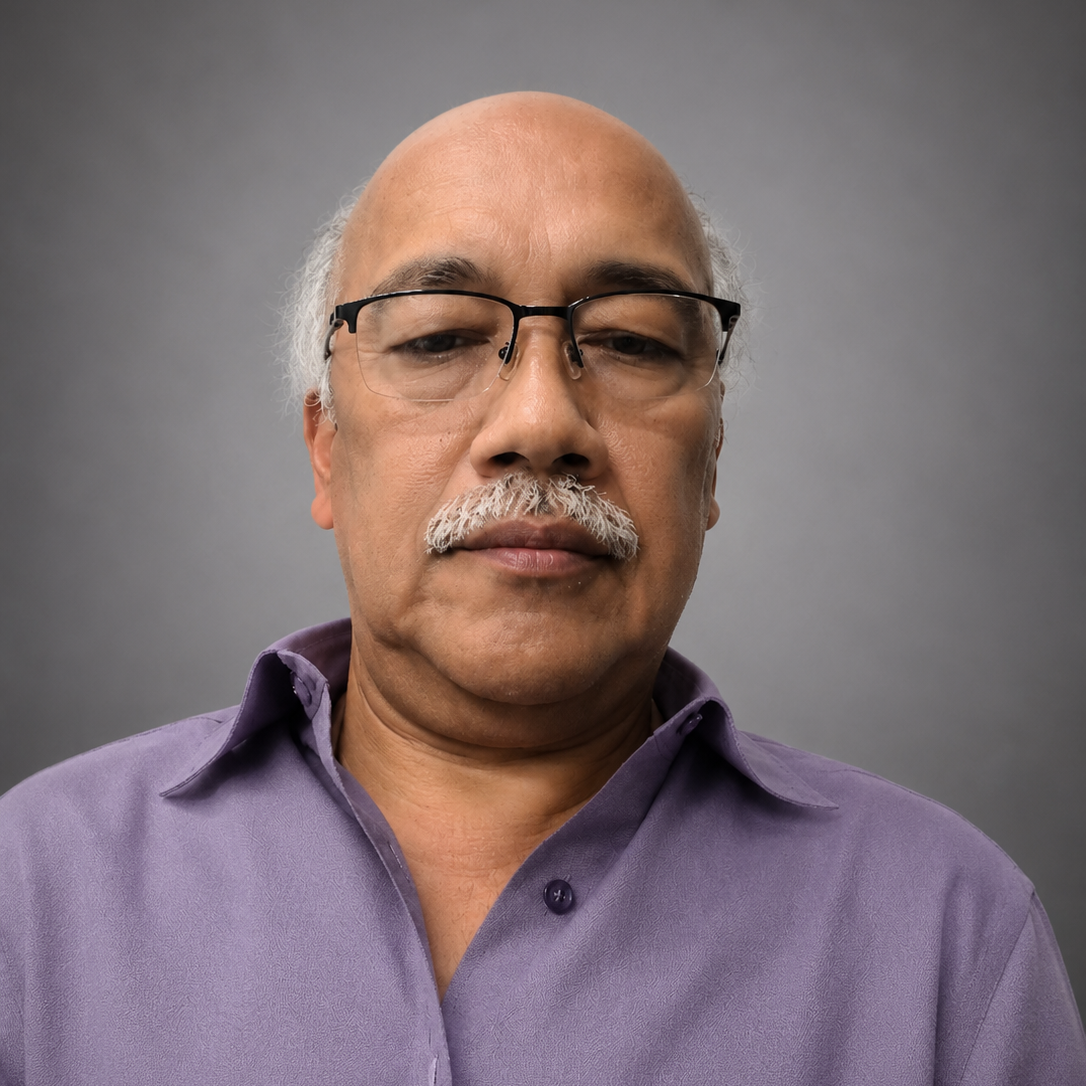 A middle-aged man with glasses, a gray mustache, and a bald head, wearing a purple button-up shirt, looking at the camera against a plain gray background.