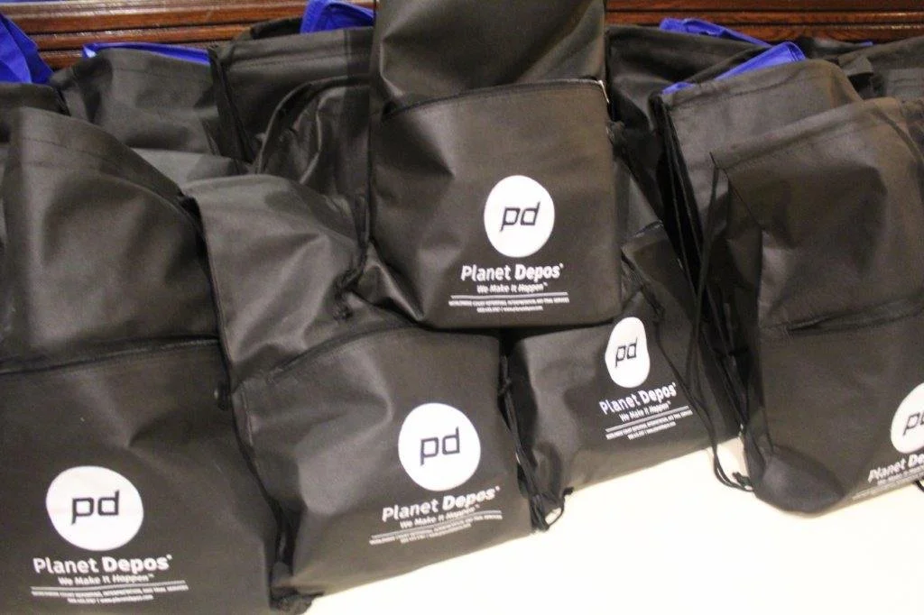 Black bags with the Planet Depo's logo stacked on a flat surface.