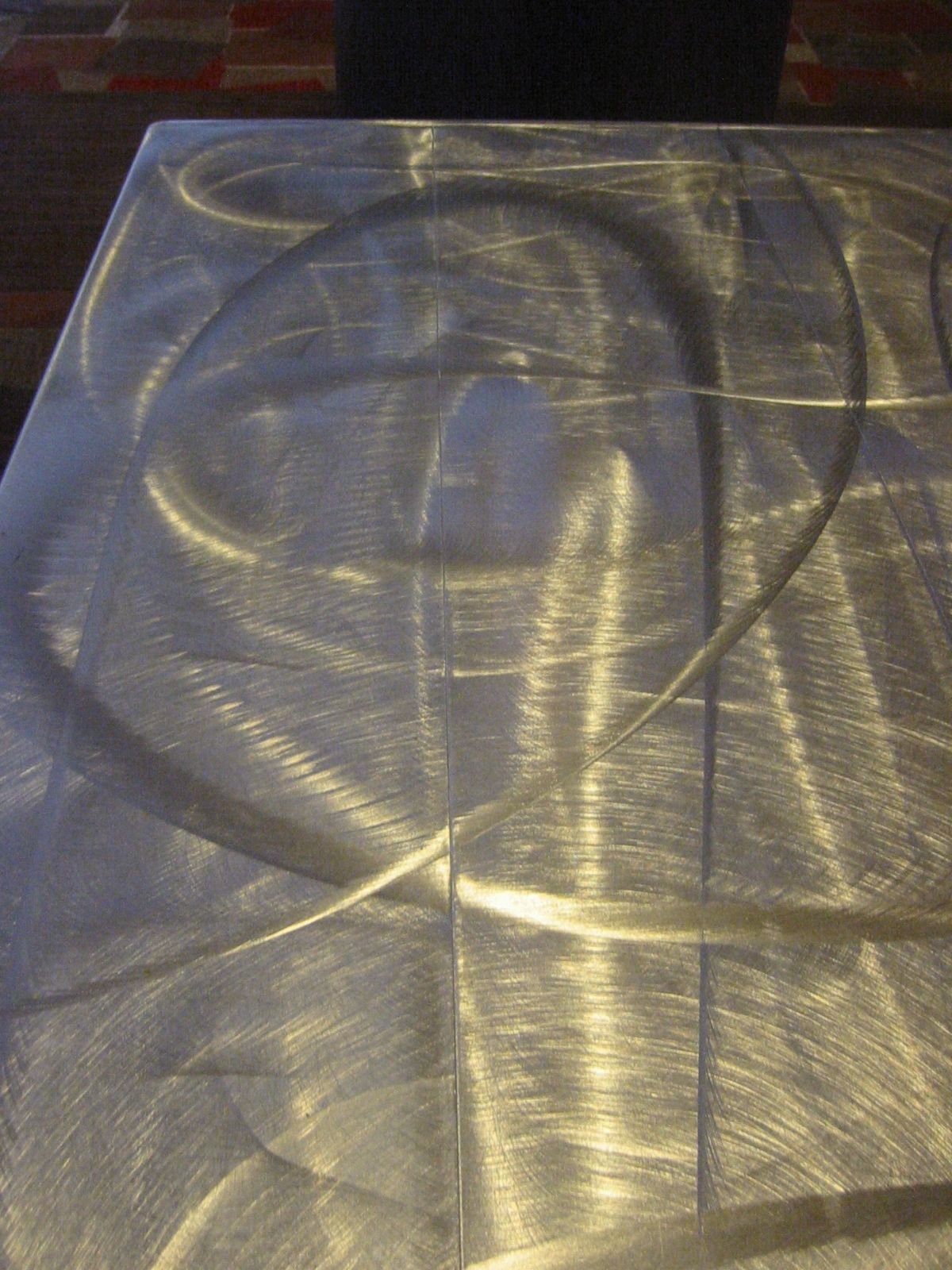 Close-up of a metallic surface with a circular pattern and light reflections.
