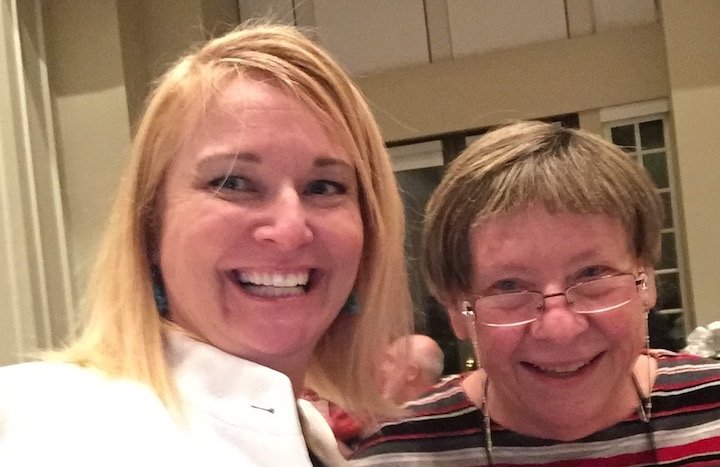 Two smiling women taking a selfie together at an indoor event.