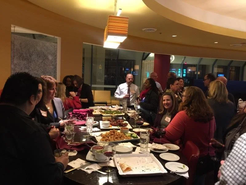 People gathered around a dining table at a restaurant or banquet setting for a meal or celebration.