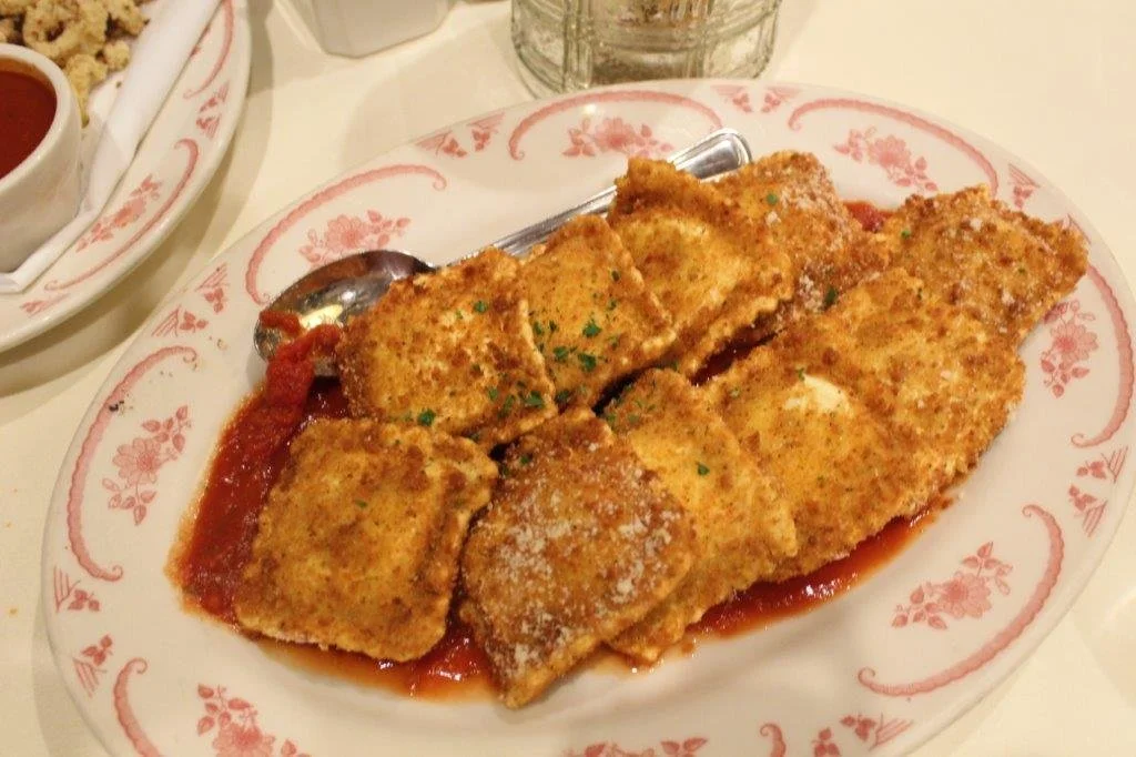 Plate of breaded and fried fish fillets with red marinara sauce.