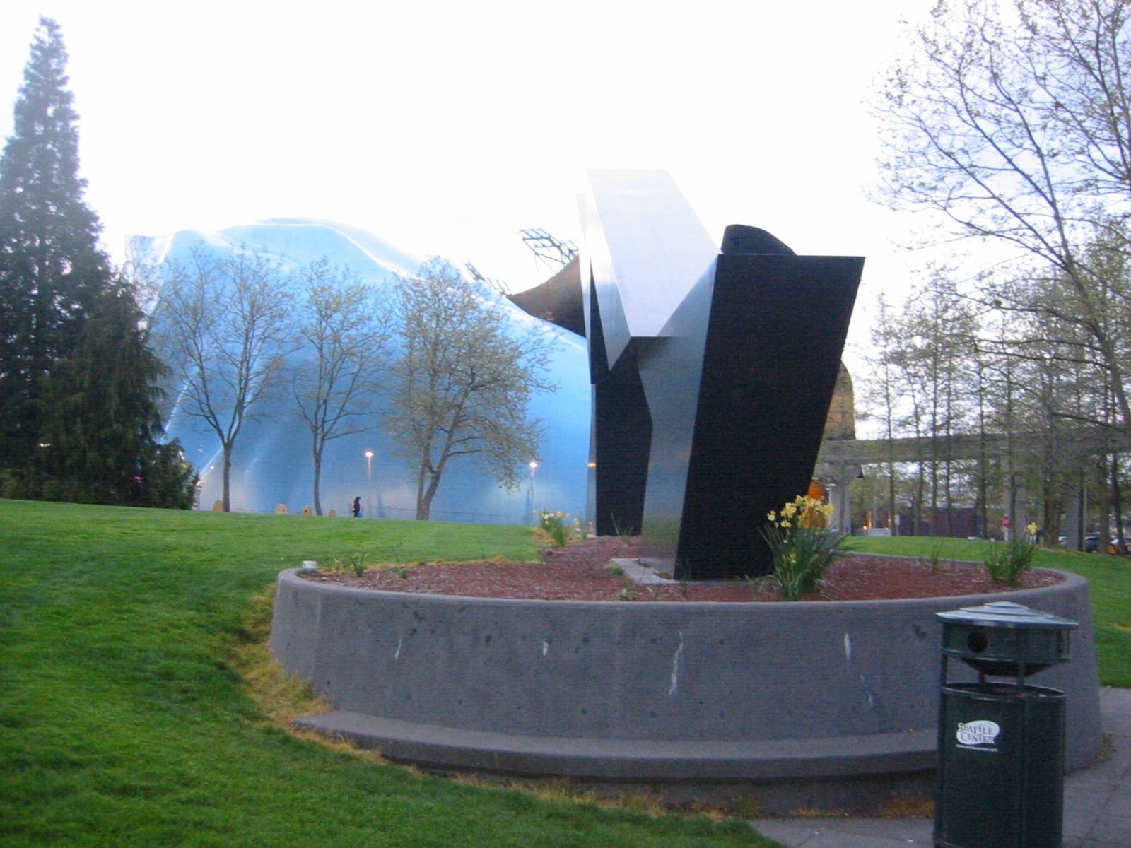 Sculpture in a park at sunset with trees and grass
