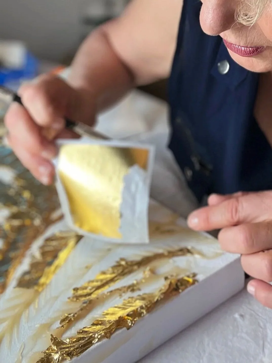 Emanuela Hauth applying gold leaf by hand while creating an original Auric Art piece.