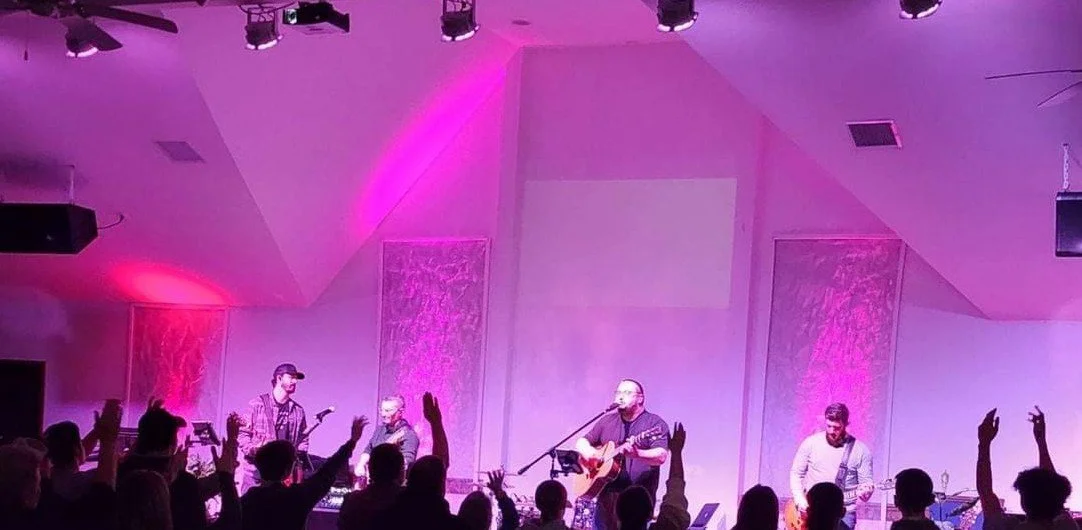 Stars Burn Down performing on stage with audience raising hands in a dimly lit venue with pink and purple lighting.