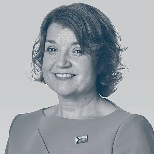 Black and white portrait of a woman smiling, wearing a dress and a pin on her chest.