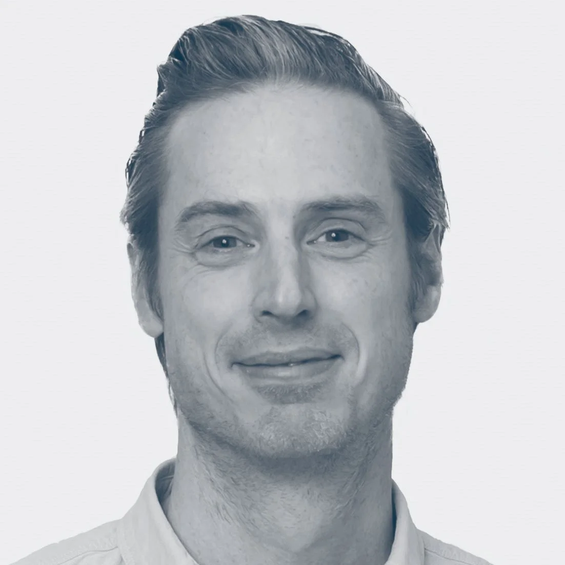 Black and white portrait of a smiling man with short, slicked-back hair